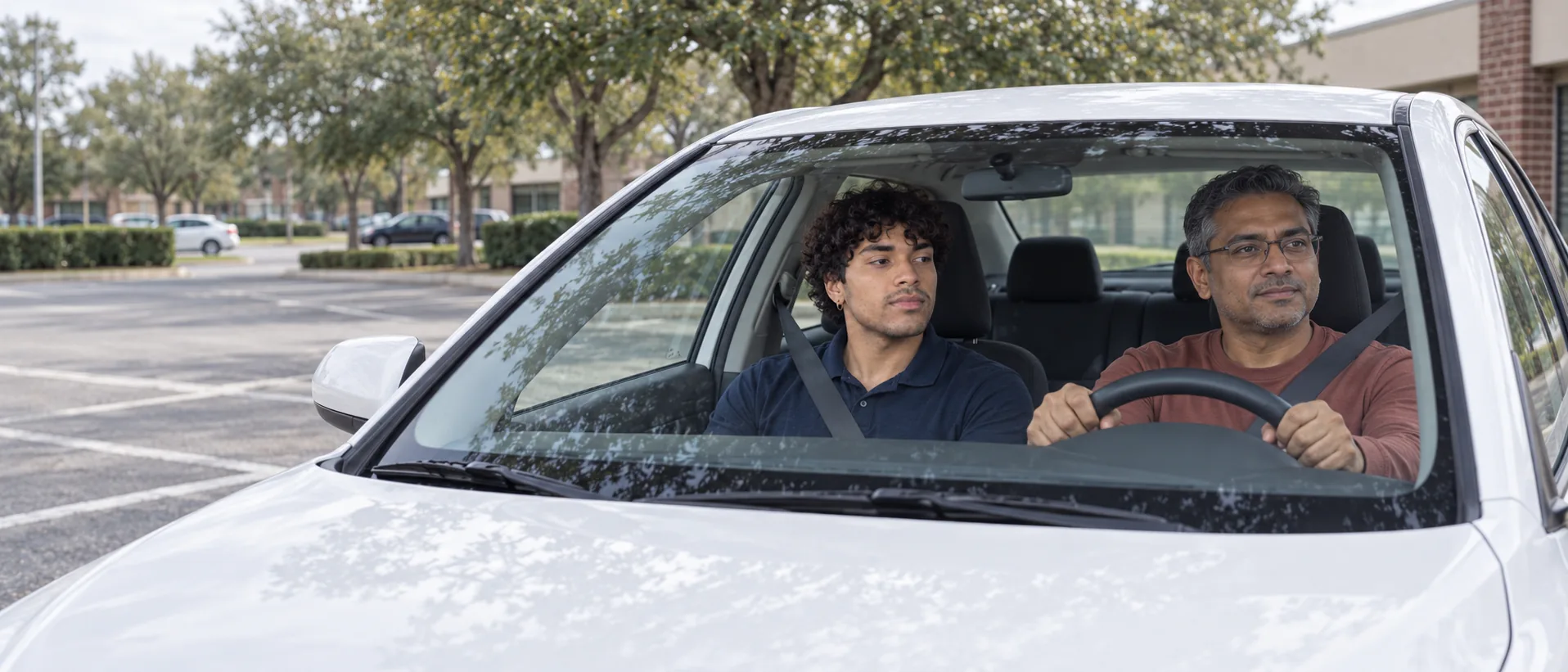Adult student driving a white Camry with a Best Driving School instructor in the passenger seat